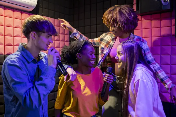 stock image lively group of friends sings and laughs together during a karaoke session, enjoying the fun atmosphere.