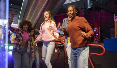 Bir grup arkadaş Arcade 'de dans ediyor ve eğleniyor, bir grup genç arkadaş atari salonunda dans ediyor ve eğleniyorlar, gülücükler ve hareketlerle kutluyorlar..