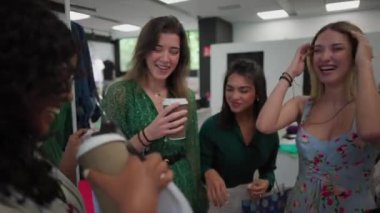 Dört genç, çok kültürlü kadın bir mağazada alışveriş yaparken ve giysileri incelerken sohbet ediyorlar. Mutlu kadınlar siyah cuma günü kıyafet alırlar.