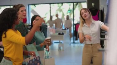 Modayı tartışan bir grup kadın moda mağazasında birlikte alışveriş yaparken dikkatle dinliyor. Giysi Mağazasında Kadın Alışveriş ve Tartışma Moda