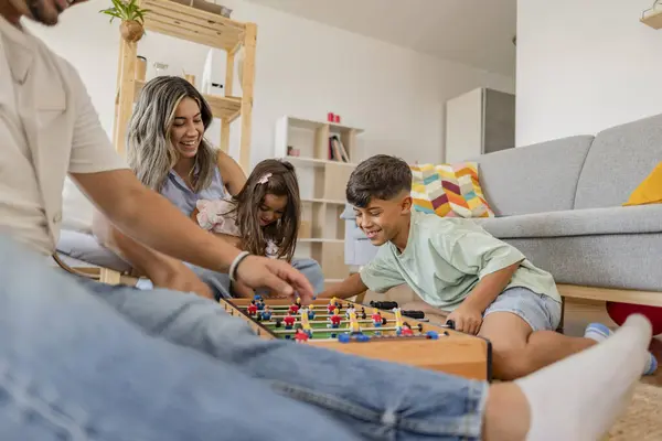 Gülümseyen Latin Amerikalı aile sıcak bir oturma odasında langırt oynuyor, kaliteli vakit geçirip kaynaşıyorlar. Latin Amerikalı aile evde eğlenceli bir langırt oyunu oynuyor.