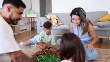 Latin Amerikalı aile bir masa futbolu maçının etrafında toplandı, oturma odalarında eğlenceli ve eğlenceli bir an paylaştılar..