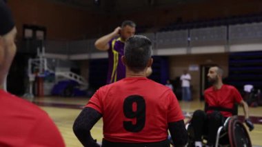 Tekerlekli sandalyedeki rugby oyuncusunun 9 numaralı kırmızı formayla iç sahadaki bir takım antrenmanında....