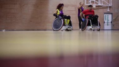 Üç tekerlekli sandalyeli rugby atleti bir oyun sırasında sahaya iniyor.