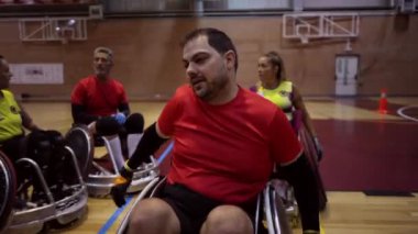 Tekerlekli sandalye basketbol takımı spor salonunda antrenörlerini dinliyor.