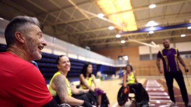 Tekerlekli sandalye basketbol takımı mola sırasında antrenörlerinin talimatlarını dinliyor.