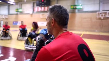 Tekerlekli sandalye koçu kırmızı üniforma giyiyor antrenman sırasında oyun stratejisini düşünüyor.