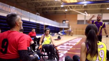 Tekerlekli sandalye basketbol takımı antrenman sırasında koçlarının taktik talimatlarını dinliyor.