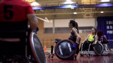 Tekerlekli sandalye sporcularından oluşan bayan takım spor salonunda antrenman yaparken koçlarının tavsiyelerini dinliyor.