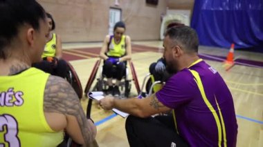 Tekerlekli sandalye basketbol takımı mola sırasında antrenörlerini dinliyor.