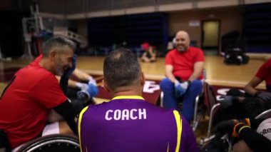 Tekerlekli sandalye basketbol koçu mola sırasında takımıyla konuşuyor.