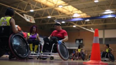 Tekerlekli sandalye ragbi takımı maçtan önce koçlarının taktik talimatlarını dinliyor.