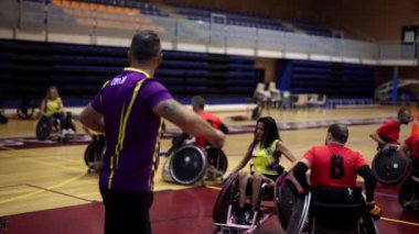 Tekerlekli sandalye basketbol koçu bir mola sırasında takımına oyun stratejisini açıklıyor.