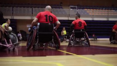Tekerlekli sandalye basketbol takımı maç boyunca sahada bekliyor, oynamaya hazır.