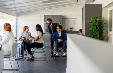 Çeşitli profesyonel gruplar, modern ofis ortamında, iş yerinde takım çalışması ve işbirliği hakkında tartışıyorlar.