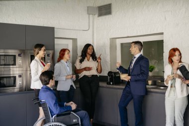 Çeşitli iş adamları modern bir ofis mutfağında mola veriyorlar. Sohbete dalıyorlar ve içeceklerin tadını çıkarıyorlar.