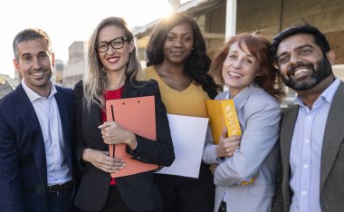 Çeşitli iş adamları dışarıda mutlu bir şekilde gülümsüyor, profesyonel olarak giyiniyor, şehir ortamında birlik ve işbirliği sergiliyor.