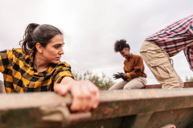 Zeytin hasadı sırasında birlikte çalışan çok ırklı çiftçiler bulutlu bir sonbahar gününde büyük metal bir kapta zeytin topluyorlar.