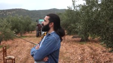 İki tane etnik çeşitlilikte genç çiftçi zeytin topluyorlar, zeytin koruluğunda ağ kullanıyorlar, ve adam hasat etmek için bir sonraki ağacı işaret ediyor.