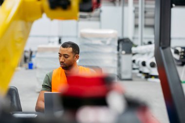 Yüksek teknoloji fabrikasında dizüstü bilgisayarı olan yetenekli robotik mühendislik programlama makineleri üretimde verimlilik ve kalite sağlıyor.