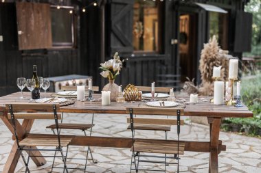 Mumlarla süslenmiş güzel bir ahşap masa. Çiçekler. Ve dışarıdaki bir akşam yemeği partisi için sıcak ve davetkar bir ortam yaratıyor arkadaşlığı kutlamak için. Çeşitlilik. Ve tatil titreşimleri