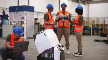 Modern bir fabrikada robotları ve otomasyonu entegre eden çok ırklı mühendisler bir tarım aracını programlıyorlar.