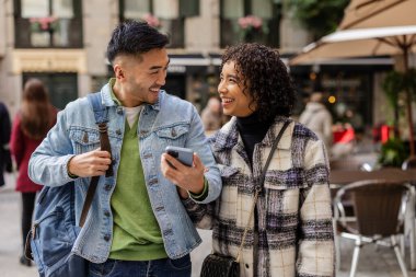 Sevgililer Günü 'nde sokakta yürürken gülümseyen ve eğlenen çok ırklı bir çift. Neşeli anları paylaşıyorlar ve birlikte anıları yakalıyorlar.