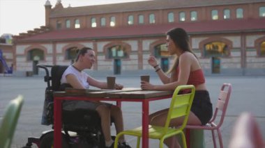 Engelli bir kadın arkadaşıyla kahve içiyor.