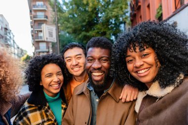 Bir grup neşeli çoklu etnik öğrenci, bir şehir caddesinde birlikte gülüyor ve eğleniyorlar, zamanlarının tadını çıkarıyorlar ve kalıcı anılar yaratıyorlar.