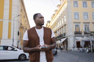 Lizbon, Portekiz 'de bir sokakta yürürken cep telefonu kullanan genç bir adam adres arıyor, taksi tutuyor ya da sosyal medyada geziniyor.