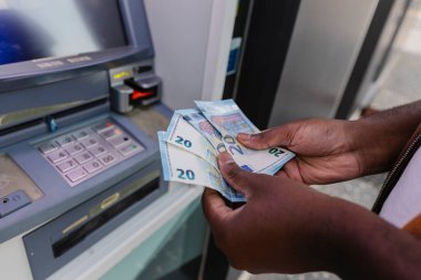 ATM 'den para çektikten sonra üç tane 20 avroluk banknot sayan, mali işlemlere ve kişisel finans yönetimine odaklanan bir adama yaklaş