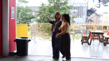 İki çok ırklı lezbiyen kadın fotoğraf kabininde fotoğraf çekiyor.