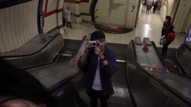 Metroda yürüyen merdivende kamerayla fotoğraf çeken genç adam.