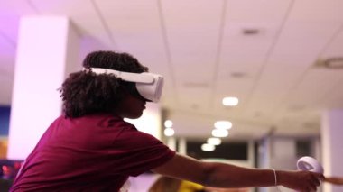 Sanal gerçeklik kulaklığı takan iki oyuncu modern bir oyun odasında heyecan verici bir oyun deneyimine daldılar. Elleriyle atış hareketlerini canlandırdılar.