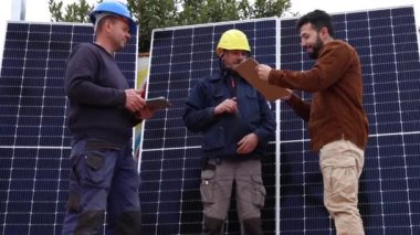 Ev çatısı, yenilenebilir enerji ve sürdürülebilir yaşam tarzı kavramının üzerine güneş panelleri kurulduktan sonra mühendisler ve müşteriler el sıkışıyor