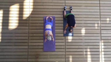 Tahta terasta bhujangasana alıştırması yapan yoga hocaları, parlak yaz sabahı seanslarında mor paspaslarda vücutları hizalayan insanlar.