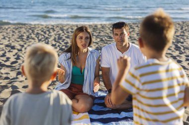 Ebeveynler ve çocuklar birlikte kaliteli zaman geçirmekten hoşlanıyorlar, yaz tatillerinde deniz kenarında çizgili bir plaj havlusunda tahmin oyunu oynuyorlar, kalıcı anılar yaratıyorlar.