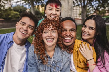 Beş neşeli, etnik çeşitliliğe sahip genç arkadaş parkta birlikte gülüp eğleniyorlar. Neşeli anılar yaratıyorlar. Arkadaşlık ve beraberlik ruhunu kucaklıyorlar.