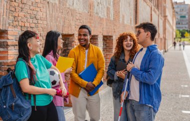 Aralarında görme engelli bir öğrencinin de bulunduğu beş mutlu, çeşitli üniversite öğrencisi kampüste birlikte duruyorlar, ellerinde kitap ve bir futbol topu, konuşuyorlar ve gülüyorlar.