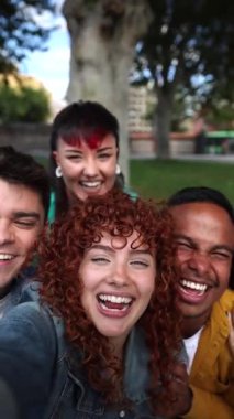 Aralarında öğrenci ve işçilerin de bulunduğu beş neşeli genç arkadaş bir parkta komik bir selfie çekiyorlar, birlikte gülüyorlar ve eğleniyorlar.