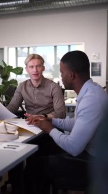 İki iş adamı, bir Afrikalı ve bir Kafkasyalı, çağdaş bir çalışma alanındaki bir masada birlikte dokümanları inceliyor, verimli bir sohbete girişiyorlar.