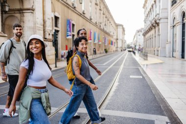 Lizbon şehir merkezindeki yaya geçidinde yürüyen bir grup genç turist yaz güneşinin tadını çıkarırken aynı zamanda canlı şehri ve eşsiz kültürünü keşfediyorlar.