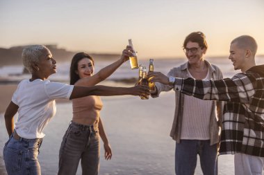 Dört neşeli arkadaş, kumsalda güzel bir günbatımının tadını çıkarırken bira şişeleriyle kadeh kaldırıyor. Arkadaşlıklarını kutluyor ve uzun süreli anılar yaratıyorlar.