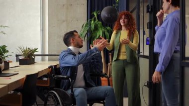 İş arkadaşları, bir iş kadınının engelli erkek meslektaşına sağlık topu getirdiği, yoldaşlığı teşvik ettiği ve destek verdiği ofis ortamında etkileşim halindedirler.