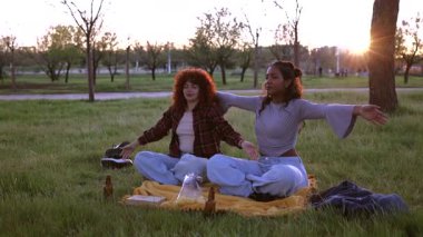 İki arkadaş gün batımında bir parkta yoga ve meditasyon yapıyorlar. Battaniyenin üzerinde oturuyorlar. Atıştırmalıklar ve içkilerle.