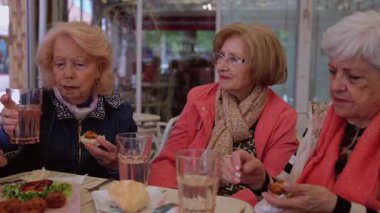 Son sınıftaki kadınlar açık bir kafede keyifli bir anı paylaşıyorlar, aperatiflerin tadını çıkarıyorlar, canlı sohbetler yapıyorlar ve birbirlerinin arkadaşlığından keyif alıyorlar.