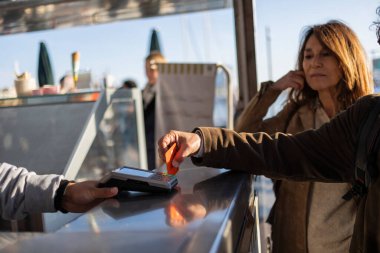Üst düzey bir adam yemek kamyonu için temas kurmadan ödeme yaparken yanında bekleyen olgun bir kadın vardı. Bulanık bir yemek kamyonu çalışanı.