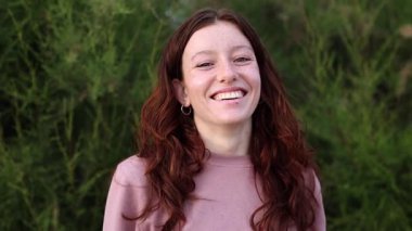 Dört neşeli genç kadın birlikte poz veriyor, gülümsüyor, gülüyor ve komik suratlar yapıyor, deniz kenarında güneşli bir günde birlikte vakit geçiriyorlar.