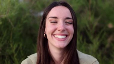 Dört neşeli genç kadın birlikte poz veriyor, gülümsüyor, gülüyor ve komik suratlar yapıyor, deniz kenarında güneşli bir günde birlikte vakit geçiriyorlar.