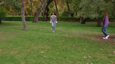 Çeşitli öğrenciler bir parkta birlikte yürürken, hoş bir sonbahar atmosferinde birbirlerine eşlik ederek daha büyük bir grup oluşturuyorlar.